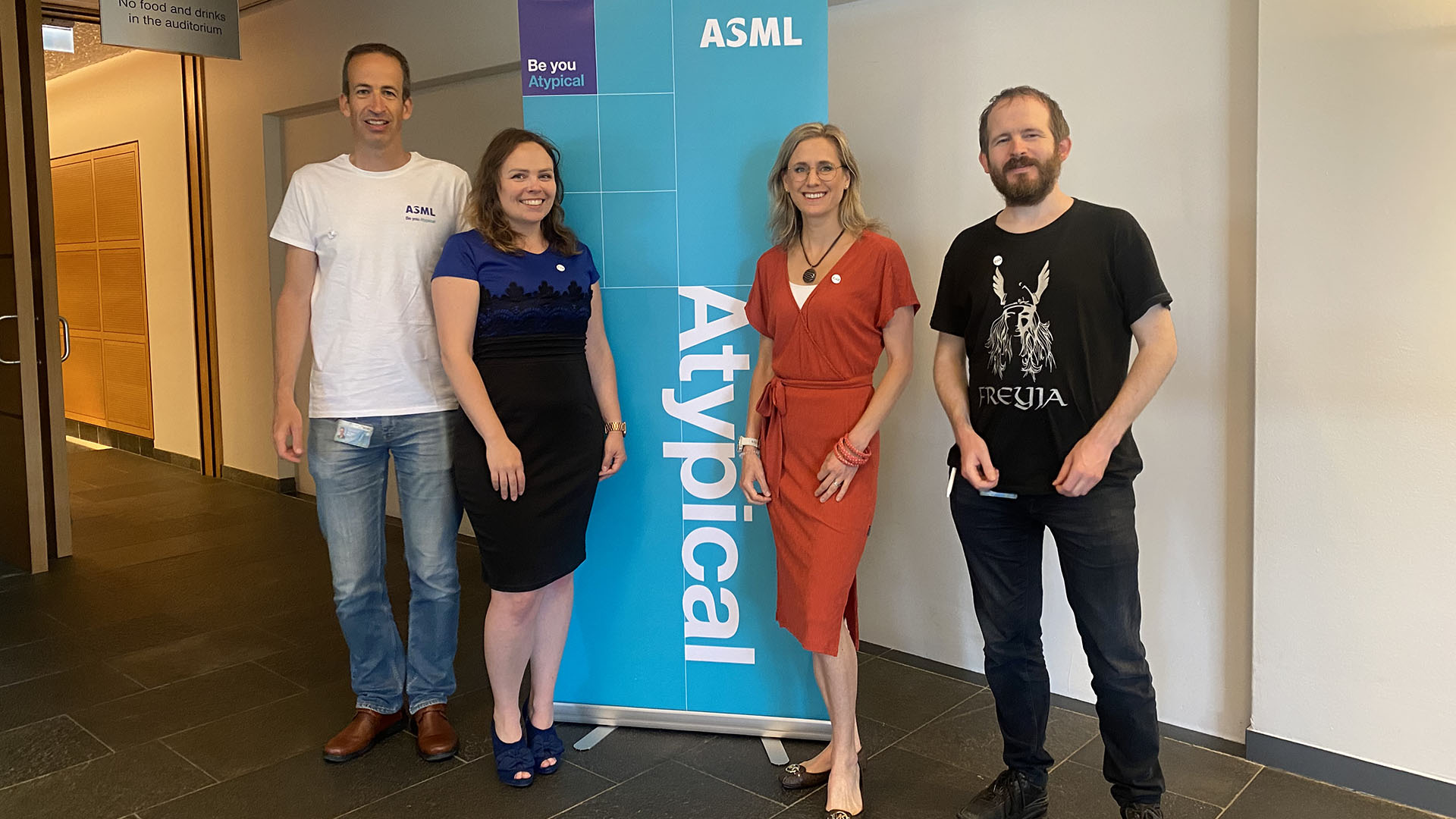 ASML神经多样性员工网络董事会成员站在带有“非典型”名称的横幅旁边。