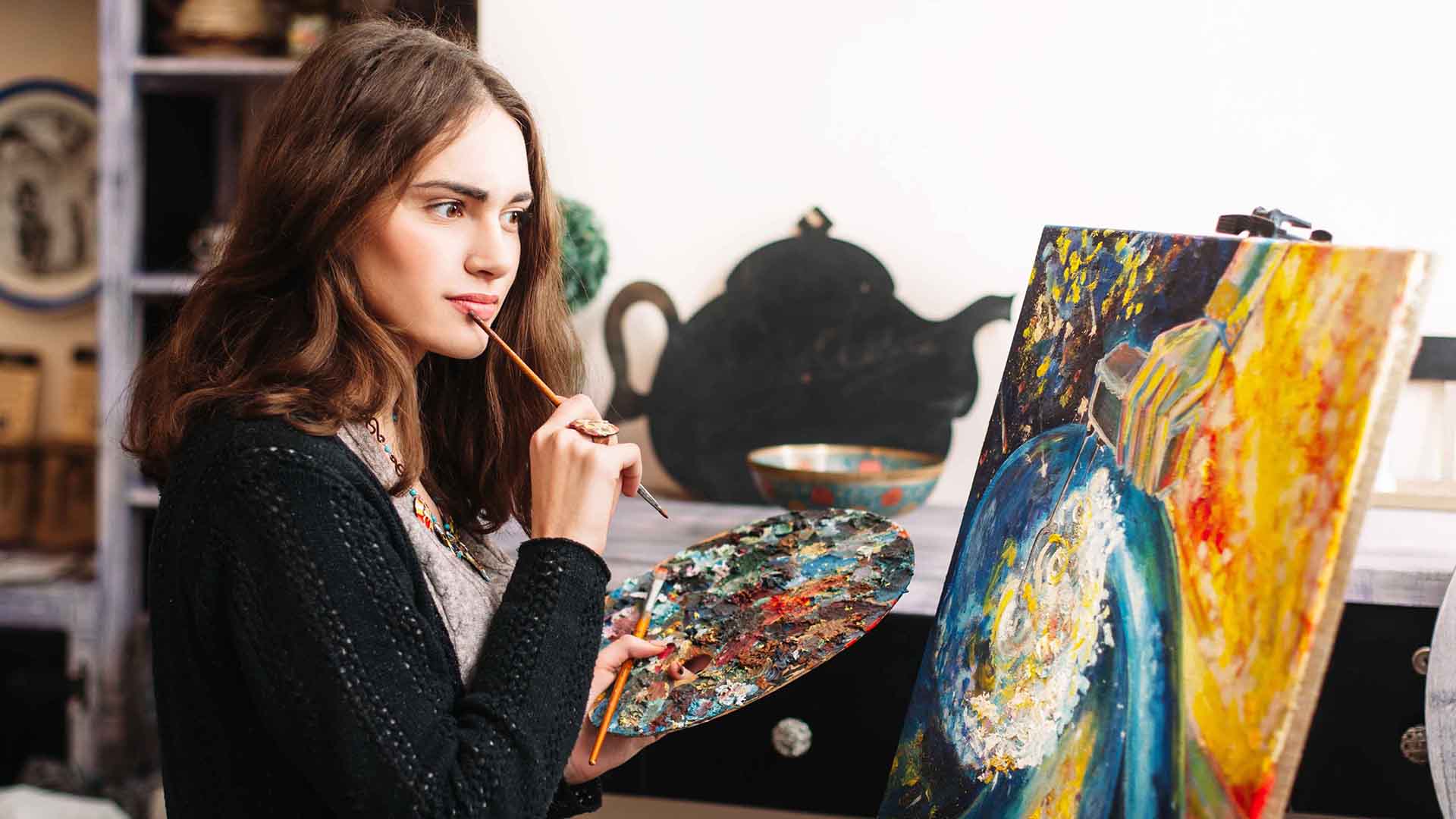 一个拿着刷子和调色板在画前的女人。