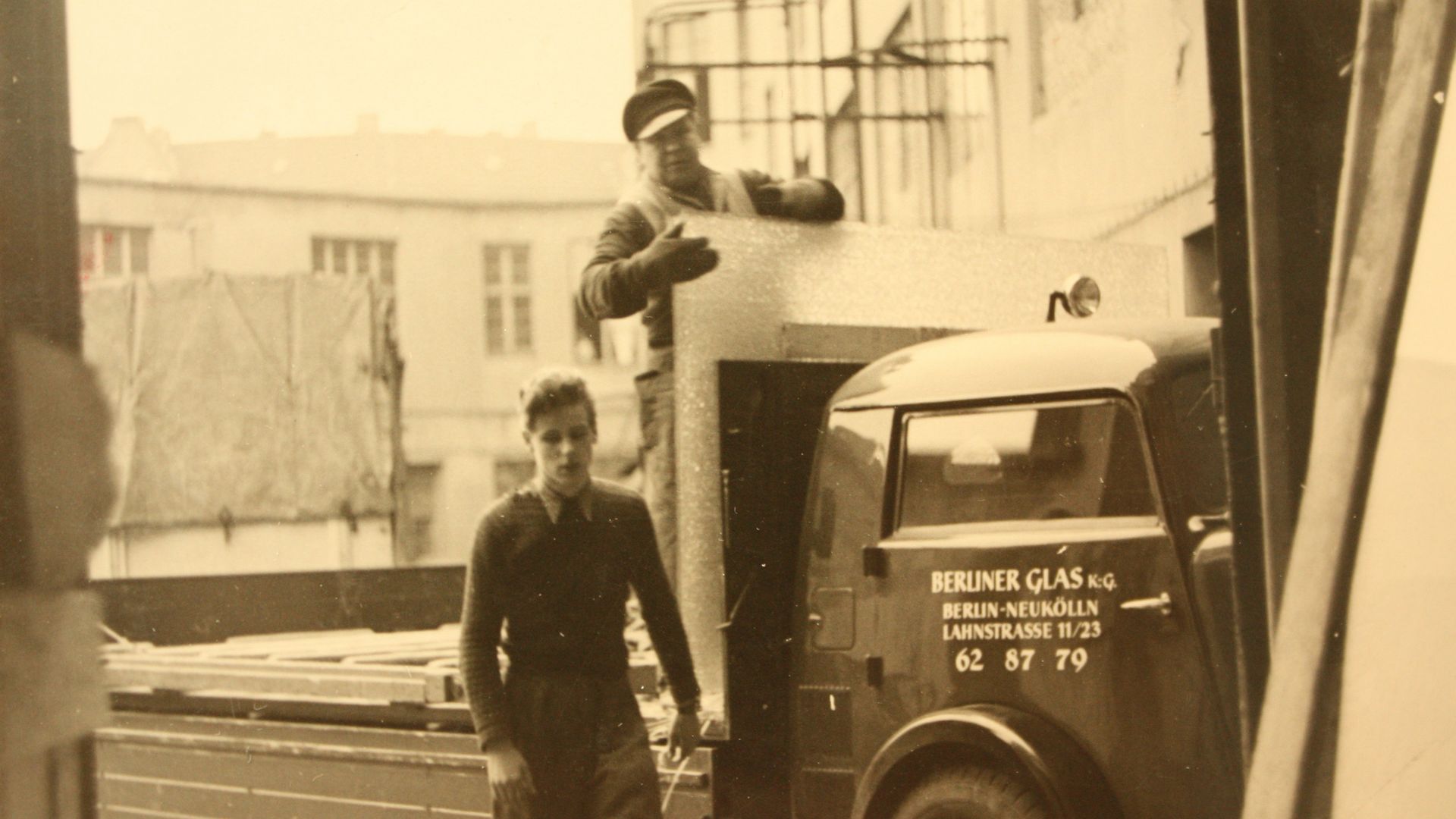 两名男子将玻璃装载到柏林人Glas卡车上的老式图片。