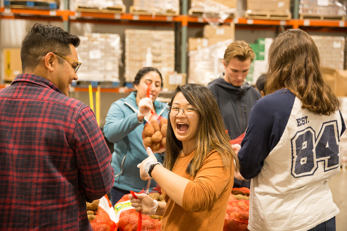 A group of plain-clothed ASML employees put together food parcels in a warehouse.