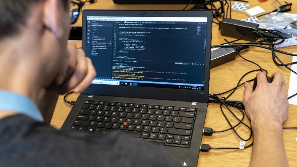 一名软件开发人员坐在屏幕前，在2018年11月在ASML的数字金色黑客马拉松上显示代码。